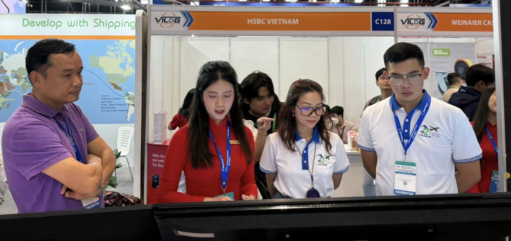 Gian hàng Softek tại VILOG 2025 với khu vực trưng bày phần mềm ERP logistics. Nhân viên đang tương tác cùng khách tham quan tại quầy, xung quanh là màn hình, bảng hiệu thương hiệu Softek và banner nhận diện.